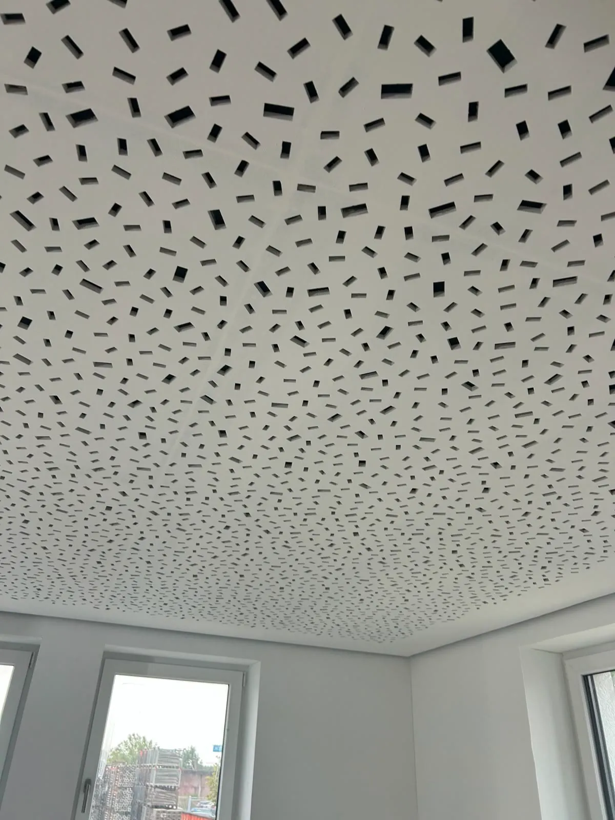 Akustikdecke mit unregelmäßiger Schlitzlochung über Fensterfront