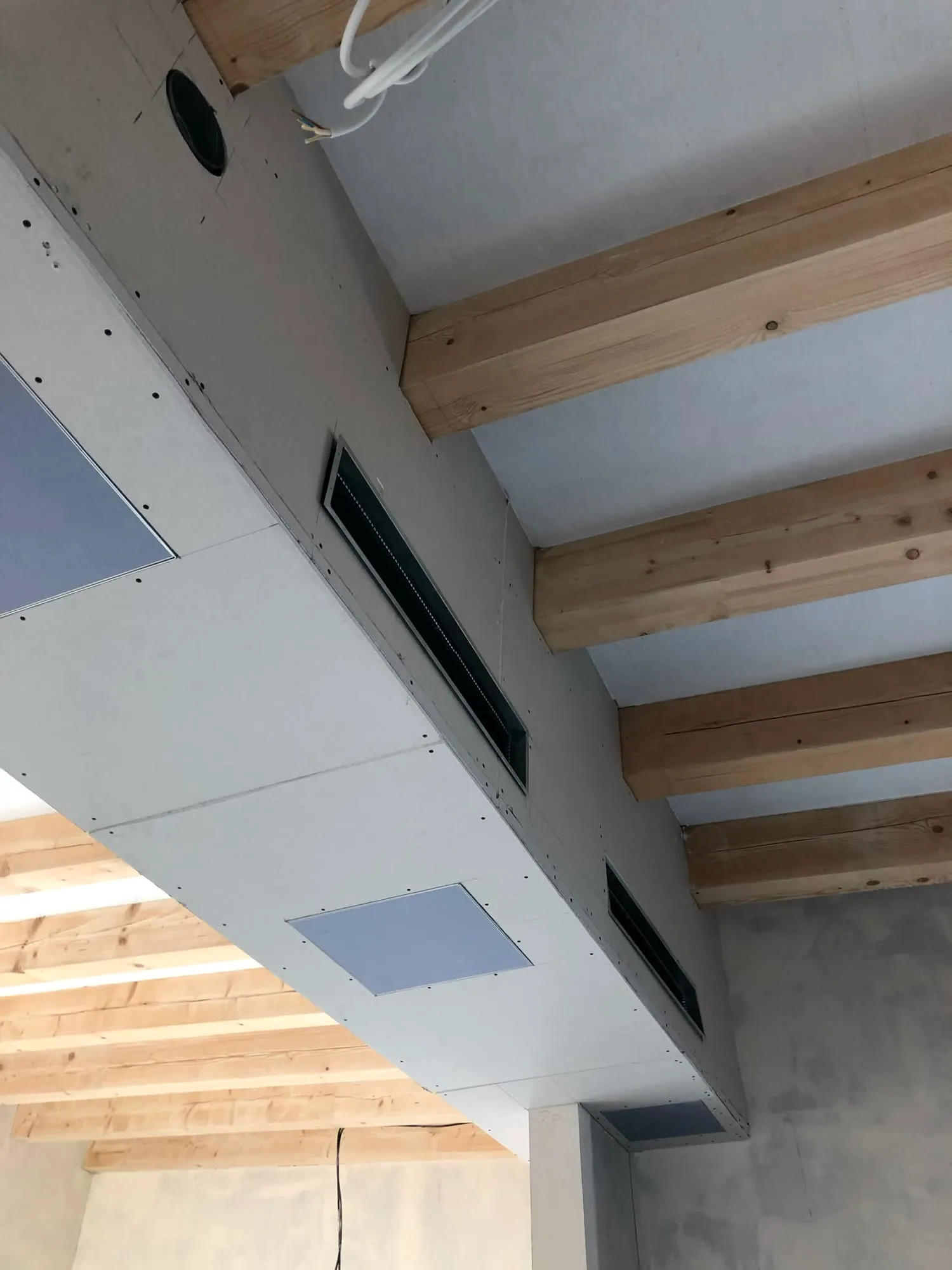 Deckenkoffer mit Lüftungsauslässen unter sichtbaren Holzbalken